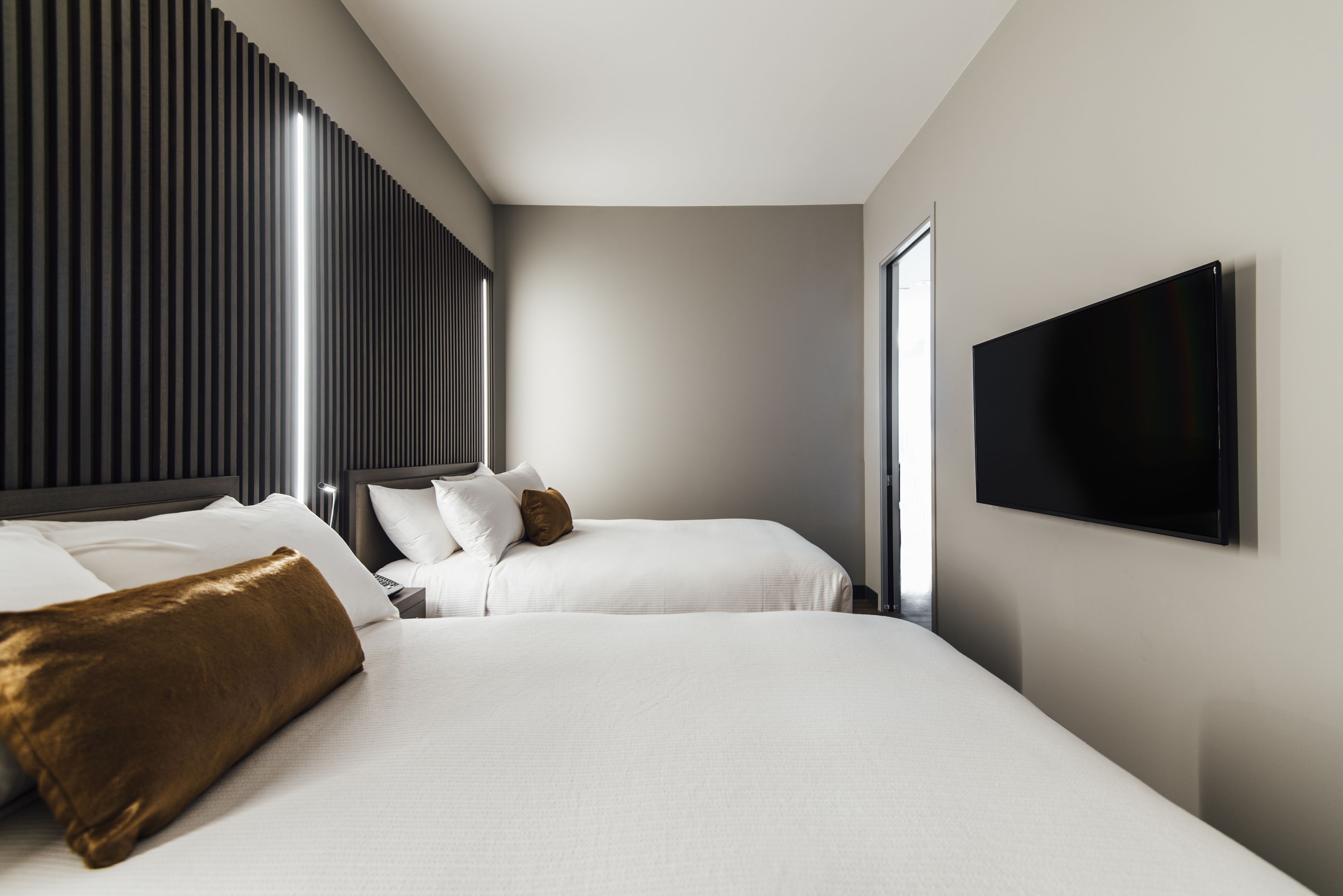 Una habitación de hotel moderna con dos camas, un televisor de pantalla plana y un ventanal grande.