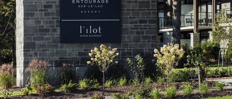 Un edificio con fachada de piedra y un letrero que dice 'ENTOURAGE SUR-LE-LAC RESORT' y 'l'ilot REFERE GOURMAND'.