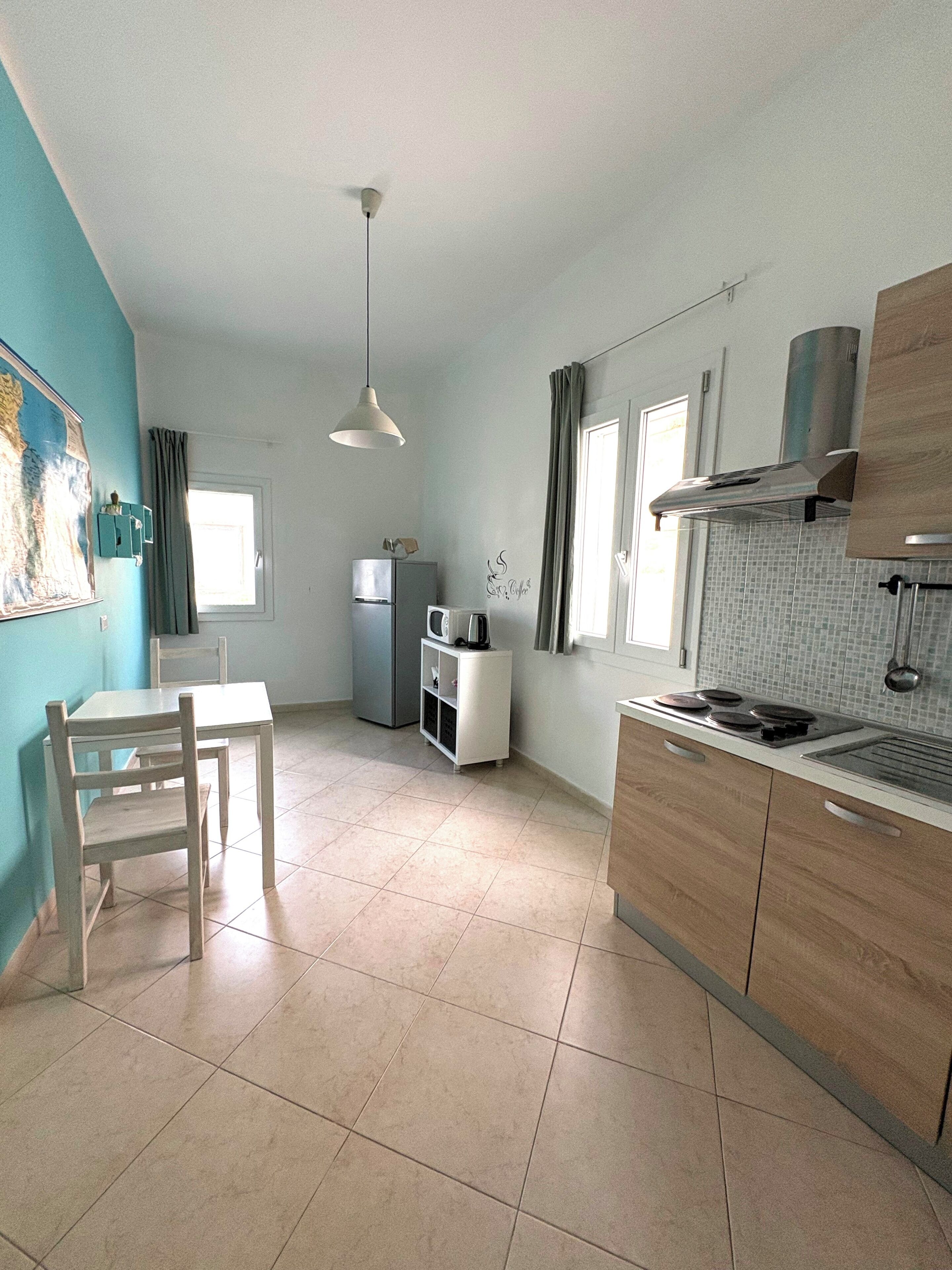 Cocina compacta con comedor, refrigerador, microondas, estufa y lámpara colgante.
