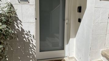 Una puerta blanca con un letrero que dice “Suite” arriba, un letrero azul con “Booking.com” y “Premios Familia 2020” debajo, y un felpudo pequeño en la entrada.