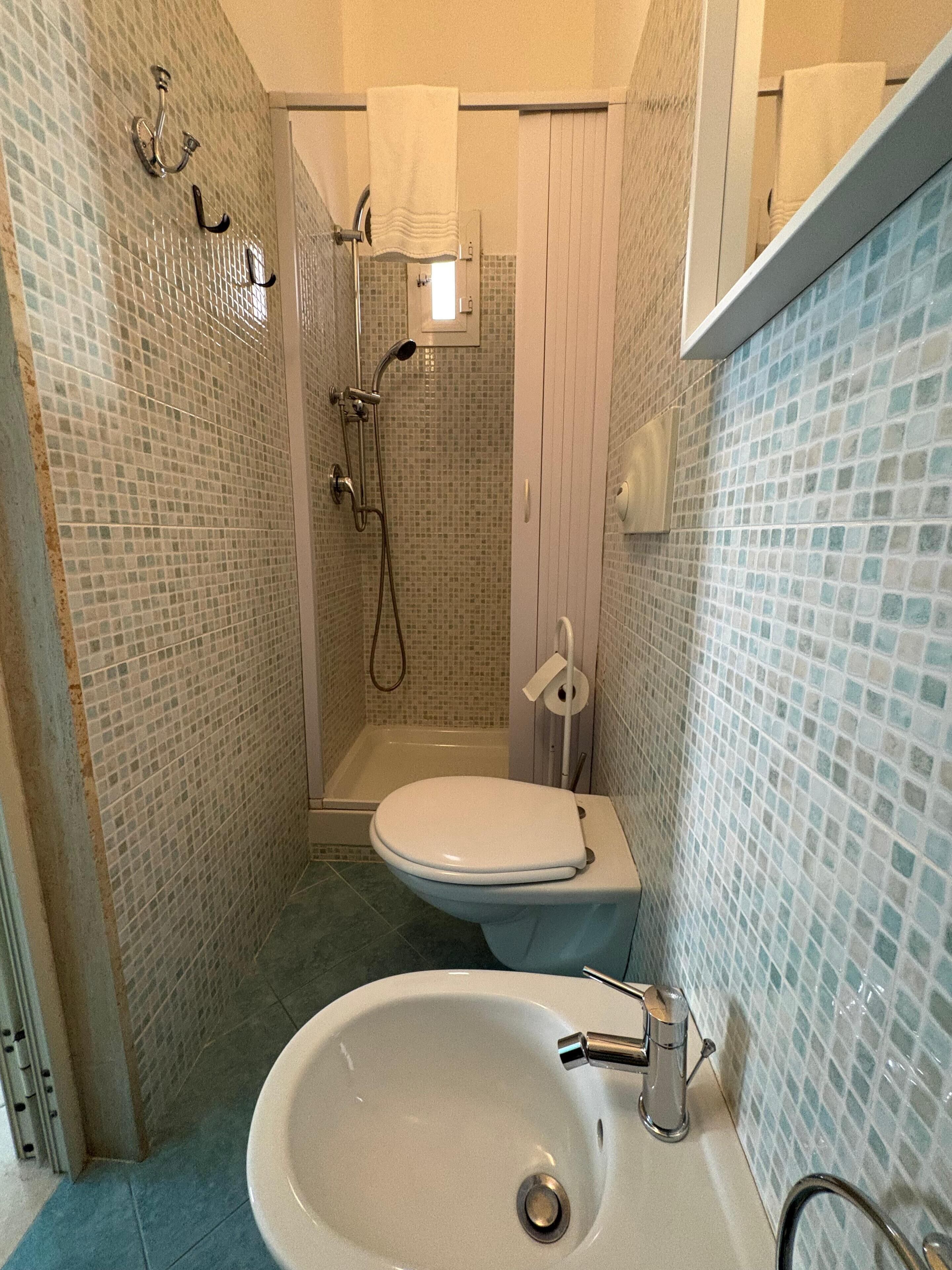 Un bagno con doccia, WC e lavandino.