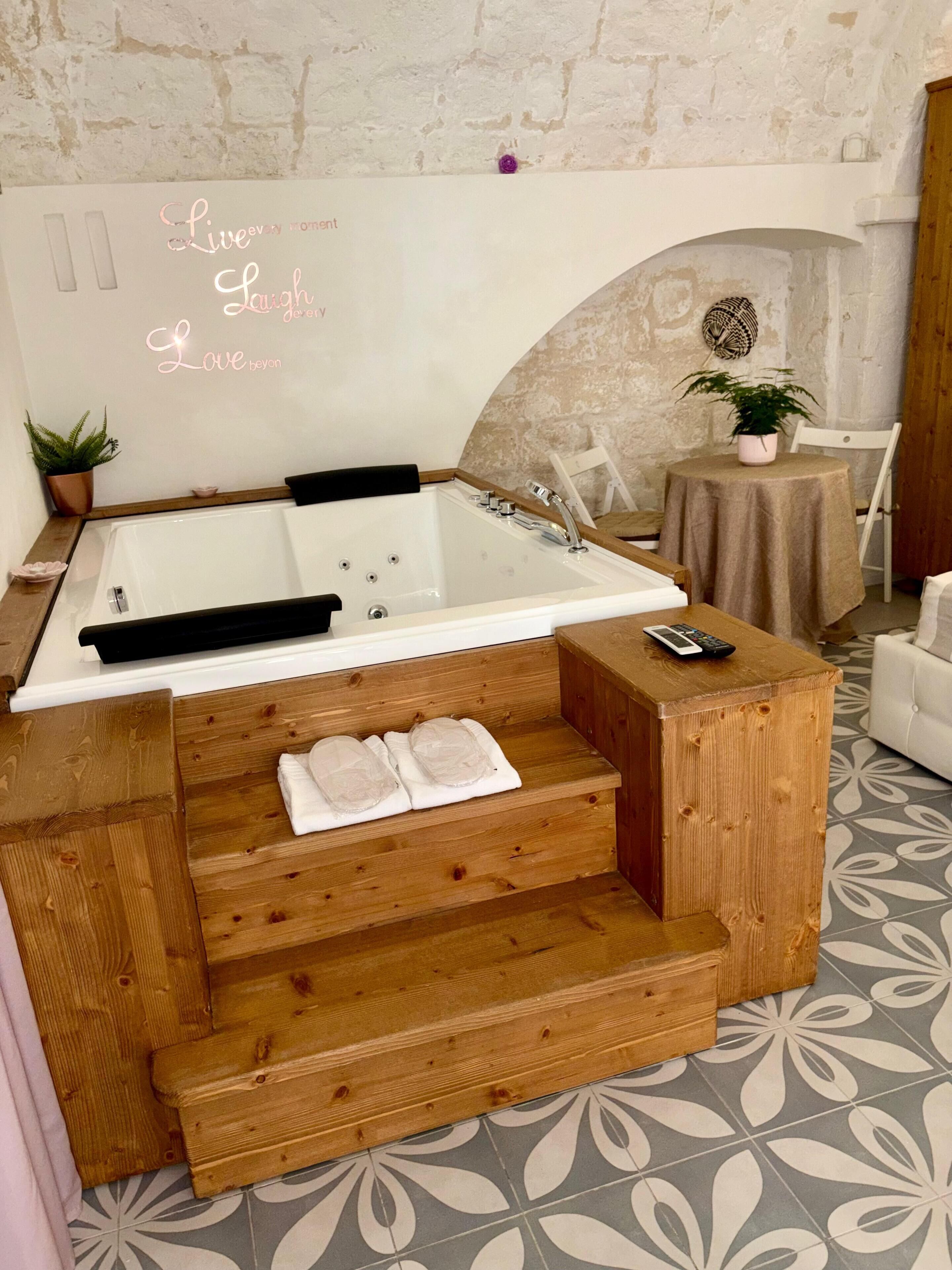 A spa area with a wooden bench, a bathtub, and a small table with a plant.