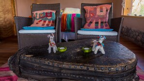 Una habitación rústica con sillas de mimbre, una mesa de madera y cojines decorativos.