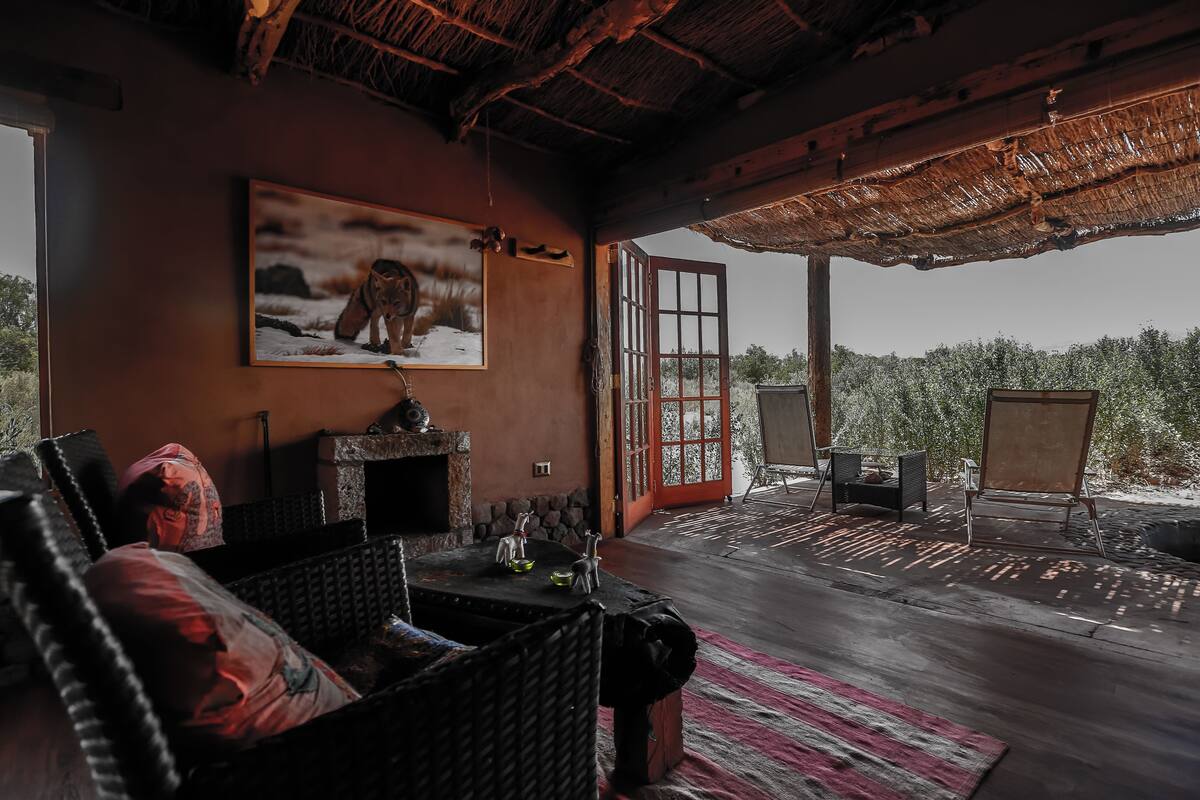 A cozy room with a fireplace, a large painting, and a view of a snowy landscape.
