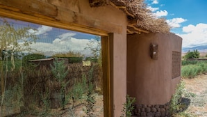 Un edificio rústico con un gran ventanal, base de piedra y techo de paja.