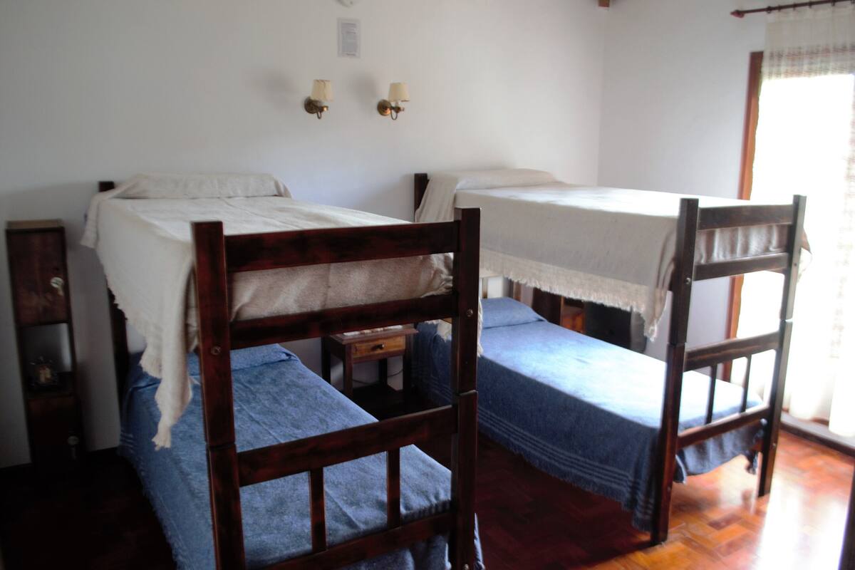Ein Zimmer mit zwei Holzbettställen, einem kleinen Nachttisch und zwei Wandleuchten.