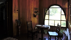 A cozy room with wooden walls, a round table, two chairs, and a large arched window.