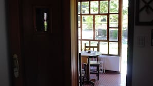 A wooden door with a sign above it, leading to a room with a window, a table, and a chair.