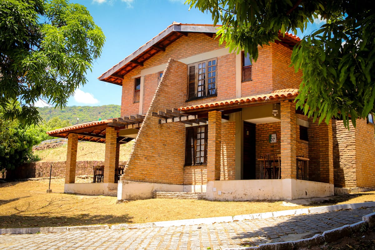A two-story brick house with a covered patio and a staircase leading to the upper floor.