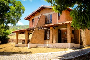 A two-story brick house with a covered patio and a staircase leading to the upper floor.