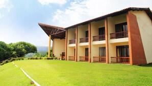 A multi-story building with a flat roof, balconies, and a well-maintained lawn. - Pasárgada Hotel (Crato)