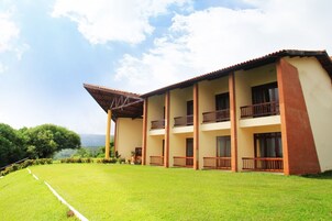 Un edificio de varios pisos con techo plano, balcones y un césped bien cuidado.