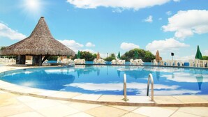 A swimming pool with lounge chairs and a thatched-roof structure. - Pasárgada Hotel (Crato)