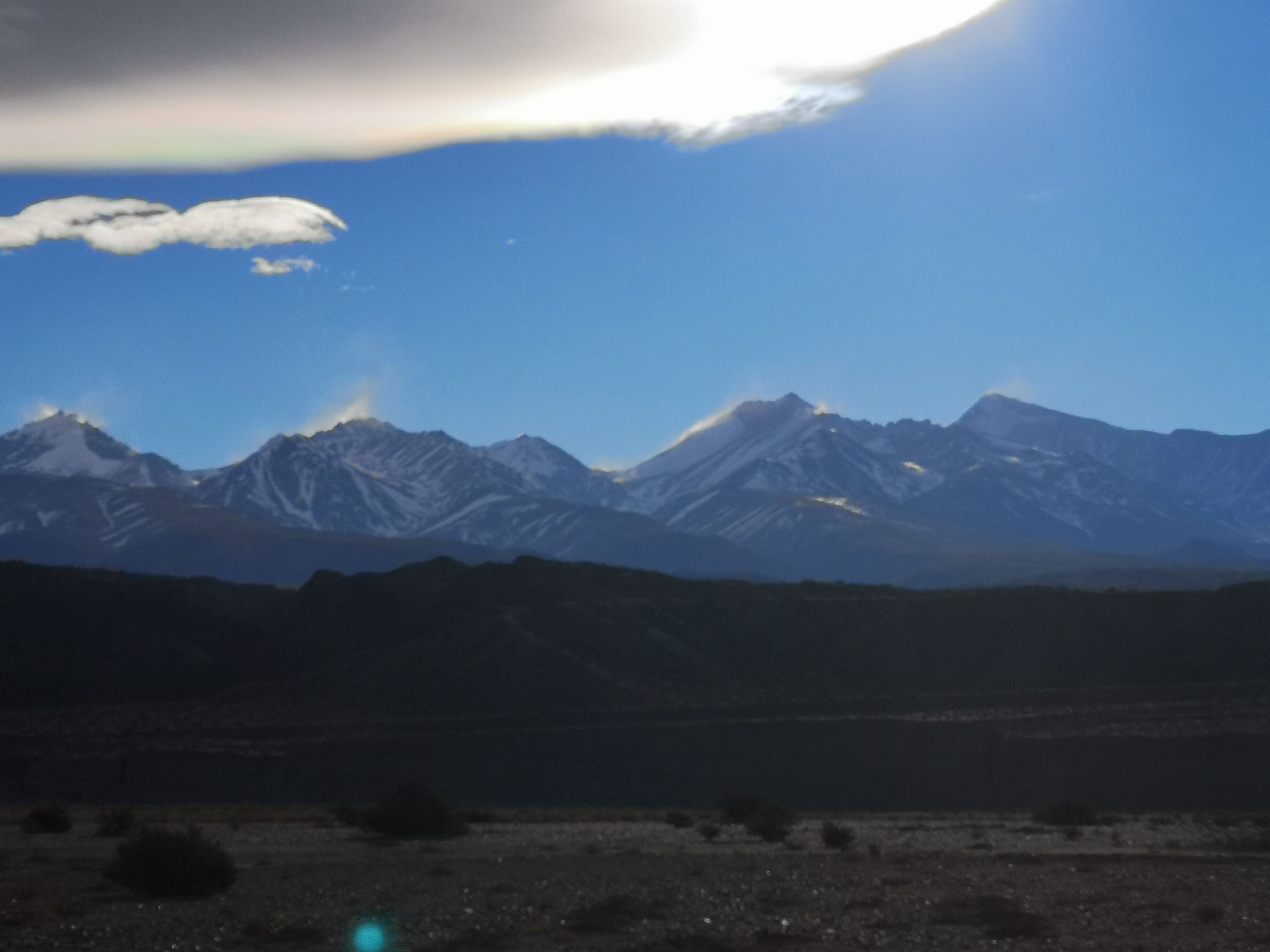 A mountain range with snow-capped peaks under a clear sky.