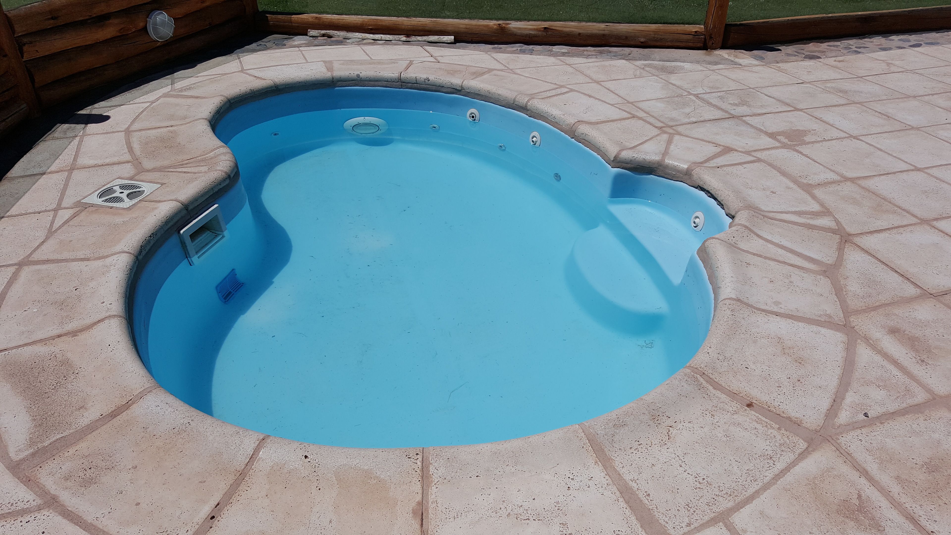 A round hot tub with a tiled patio surrounding it.