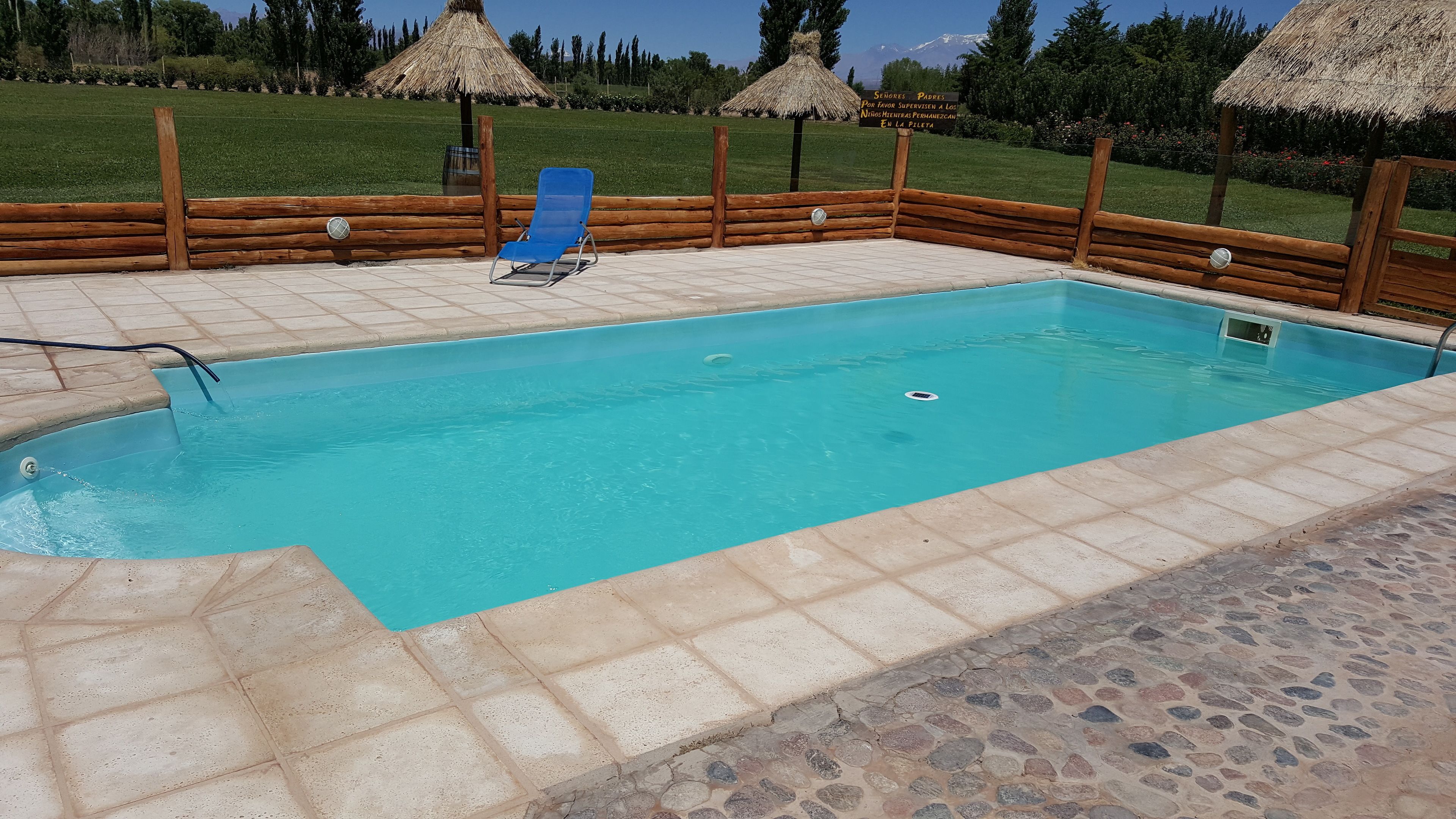A rectangular pool with a tiled edge, surrounded by a wooden fence and a stone border.
