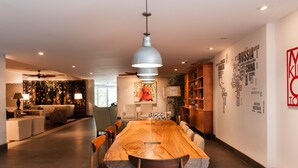 A modern dining area with a long wooden table, multiple chairs, and a large pendant light. - Splendor Stay Escalante (Mercedes)