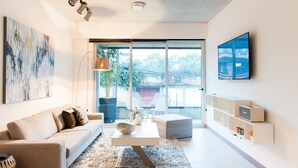 A modern living room with a sofa, coffee table, and a TV mounted on the wall. - Splendor Stay Escalante (Mercedes)