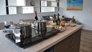 A modern kitchen with a built-in stove, a sink, and a countertop. There are various kitchen items and a painting on the wall.