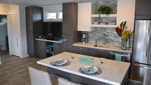 A modern kitchen with a central island, built-in appliances, and a stone backsplash.