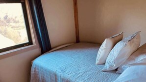 A bed with white linens and pillows in a room with a window.