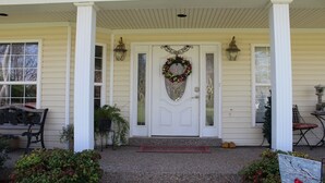 Une maison avec une porte d’entrée blanche, une guirlande et deux lanternes de chaque côté.