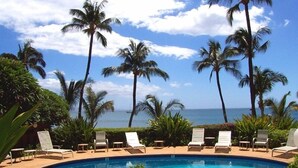 A poolside area with lounge chairs and palm trees, overlooking the ocean. - Ocean views at Kealia Resort on Sugar Beach! (Kihei)