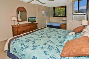 Quarto com cama, cômoda, espelho e janela com vista.