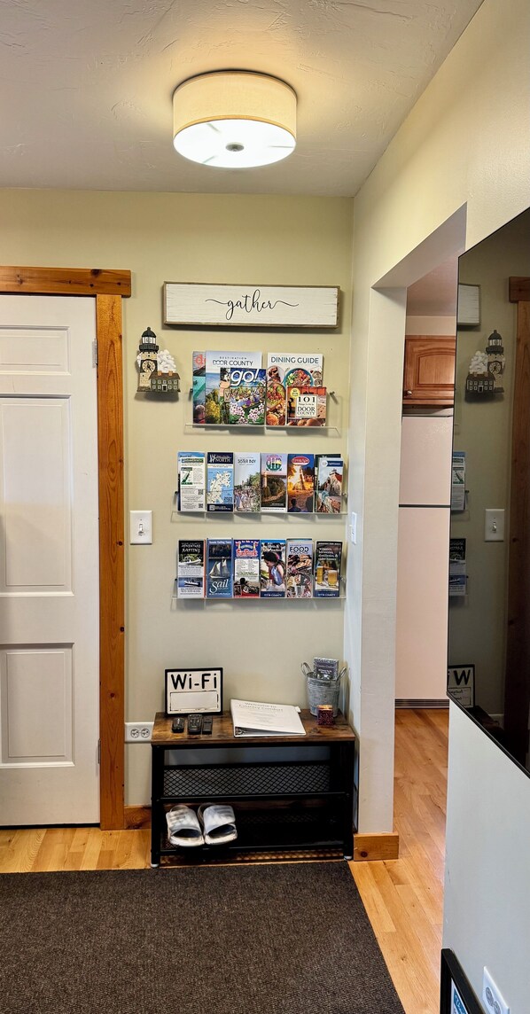 A hallway with a wooden door, a wall-mounted sign reading "gather," and a bulletin board with various pamphlets and a Wi-Fi sign.