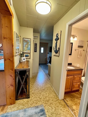 A hallway with a wooden table, a map, and a wall-mounted anchor.