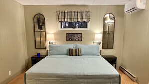 A bedroom with a large bed, two bedside tables, a window with curtains, a wall-mounted mirror, and a motivational quote sign. - Ellison Bay tranquility close to Europe Lake, Newport State Park and Beach! (Ellison Bay)