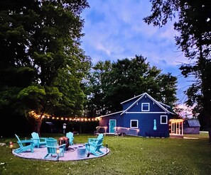 Una casa con terraza, mobiliario exterior y luces colgantes.