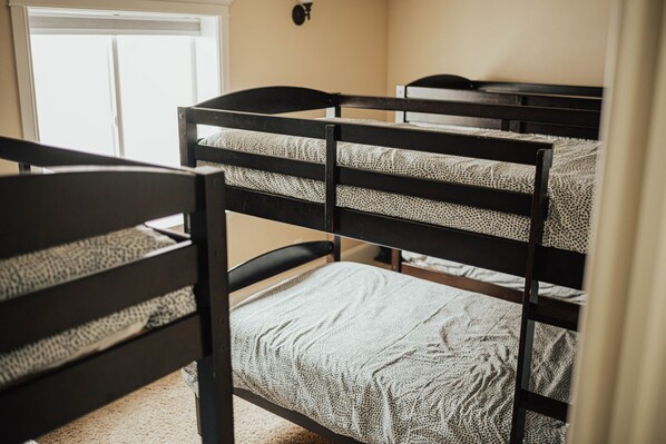 A bunk bed room with a window and a wall-mounted light fixture.