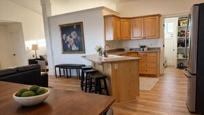 Une cuisine moderne avec des meubles en bois, un îlot central et un coin repas comprenant une table et des chaises en bois.
