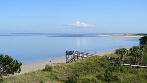 Ein Küstenblick mit einer Holzpromenade, die zu einem Sandstrand führt.