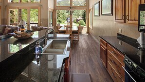 A spacious kitchen with a large island, wooden cabinets, and a view of the outdoors. - Gorgeous Townhome Views of the Slopes, Sleeps 12, Private Baths, Private Hot Tub (Whitefish)
