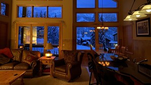 A cozy living room with a fireplace, leather furniture, and large windows offering a view of a snowy landscape. - Gorgeous Townhome Views of the Slopes, Sleeps 12, Private Baths, Private Hot Tub (Whitefish)