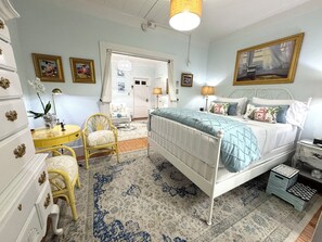 A bedroom with a bed, a chair, a dresser, a nightstand, and a lamp.