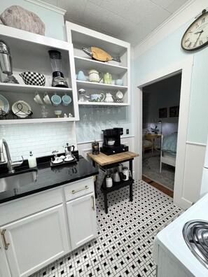 A kitchen with white cabinets, a black countertop, and a patterned floor.