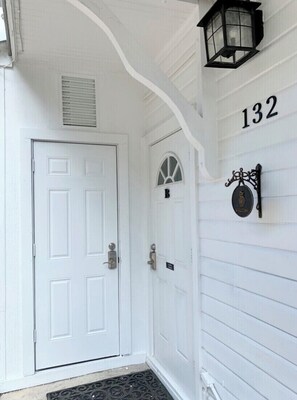 A white front door with a doormat, a mailbox, and a welcome sign on the wall. - Casa de Flora B- Relaxed Elegance in historic St Augustine 🚭 (St Augustine)