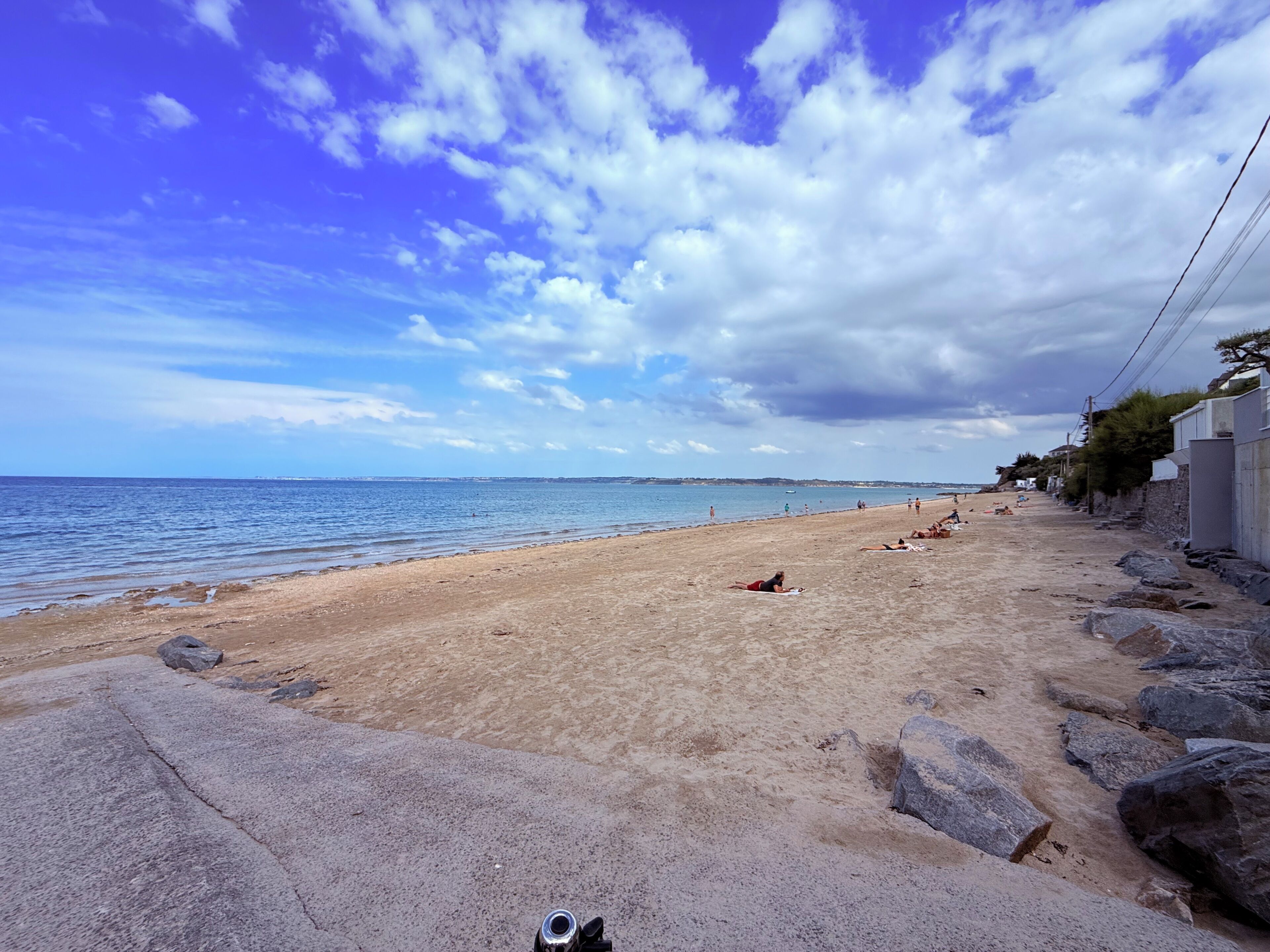 Une plage avec un ciel dégagé, une côte rocheuse et une mer calme.