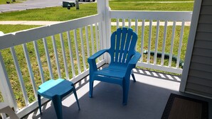 A blue plastic chair and a matching stool on a porch with a white railing. -  Gulf Shores - AFFORDABLE BEACH VACATION (Gulf Shores)