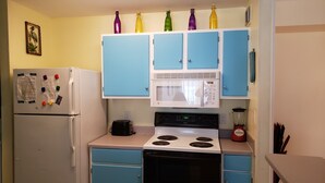 A compact kitchen with a white refrigerator, a microwave, and a stove. There are blue cabinets and a small countertop. -  Gulf Shores - AFFORDABLE BEACH VACATION (Gulf Shores)