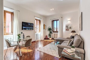 A modern living room with a glass coffee table, a sofa, and a dining area with chairs. - TERRY’S HOUSE	 Luxury Spot in Historical Rome (Roma)