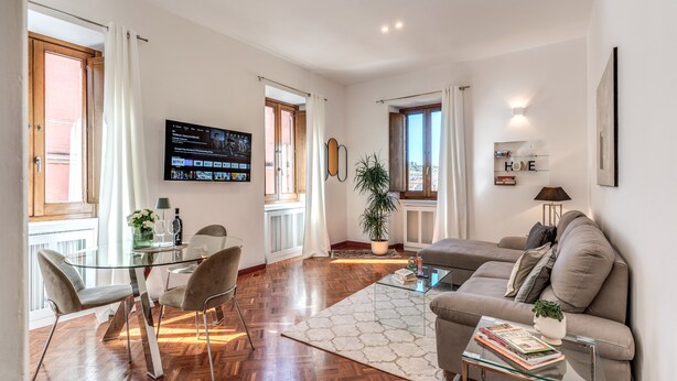 Een moderne woonkamer met een glazen salontafel, een bank en een eethoek met stoelen en een glazen tafel.