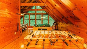 Ein Raum mit Holzboden, einer Kicker-Tischtennisplatte, einem Billardtisch und einer Snookertisch.