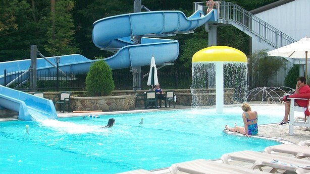 Une piscine avec un toboggan et une fontaine.