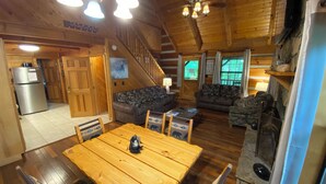 L’intérieur chaleureux d’un chalet comprend une table à manger en bois, deux canapés, un coin cuisine et un escalier.