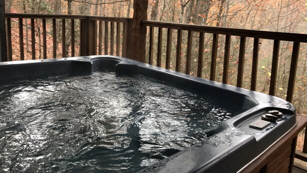 Un bain à remous sur une terrasse en bois, avec vue sur la forêt.