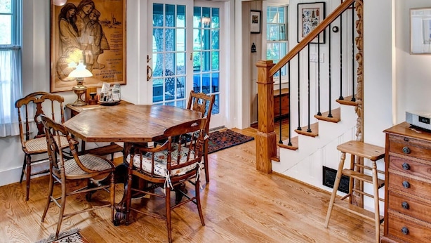 Un espace repas comprenant une table et des chaises en bois, un lustre et un escalier avec des rampes en bois.